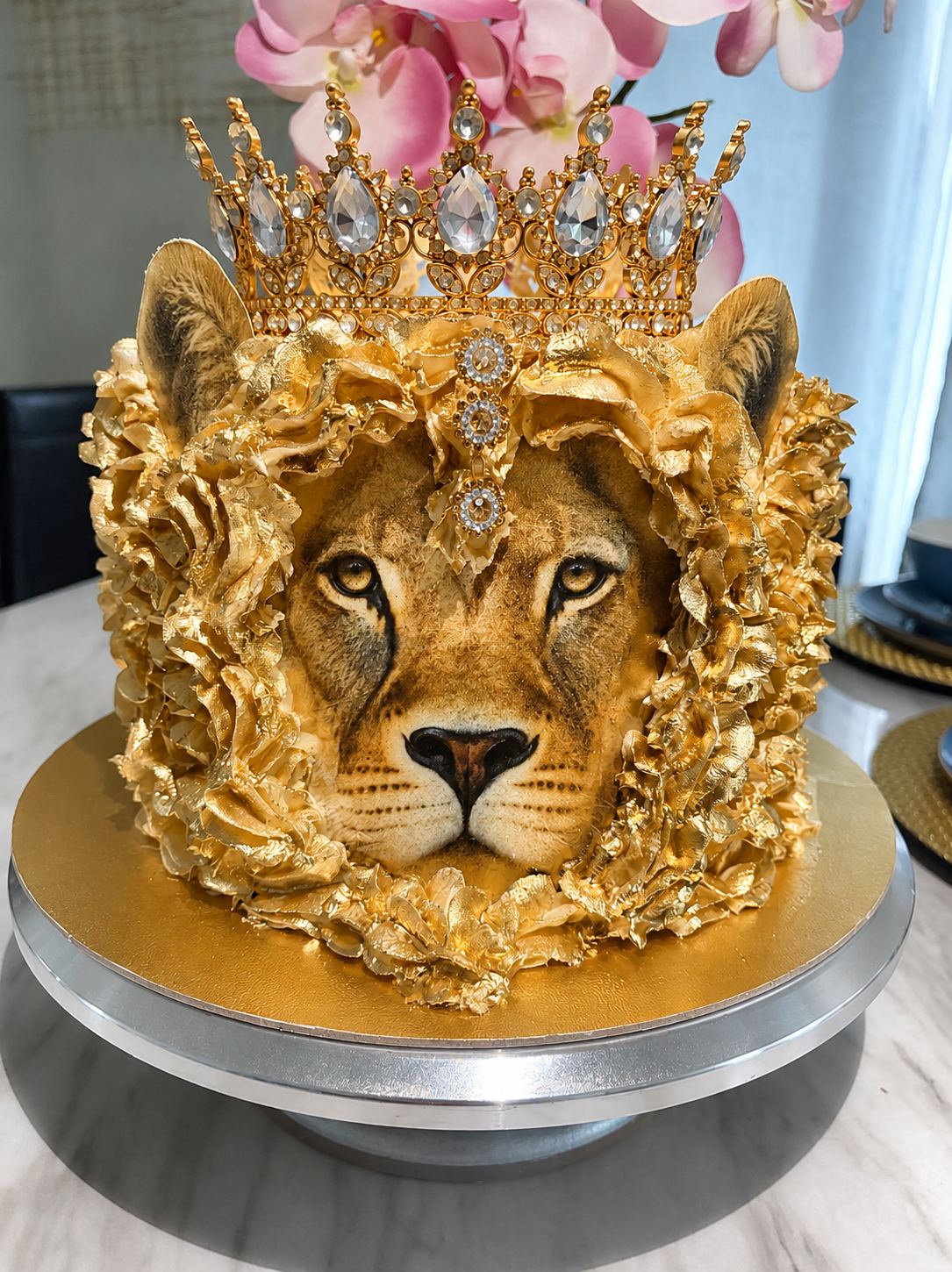 Nica's crowned lion cake: a lion face framed by a ruffled gold buttercream mane, with a jeweled crown on top.