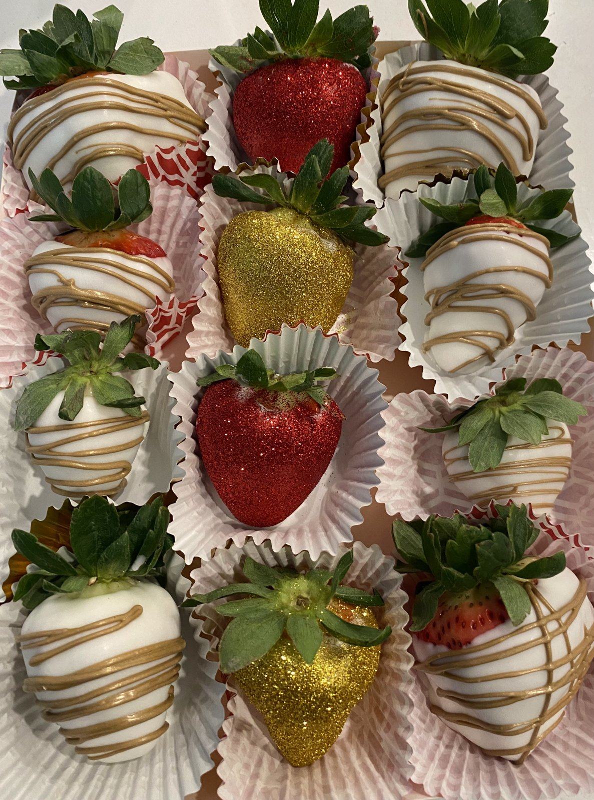Box of chocolate-covered strawberries in white with gold drizzle, red glitter, and gold glitter.