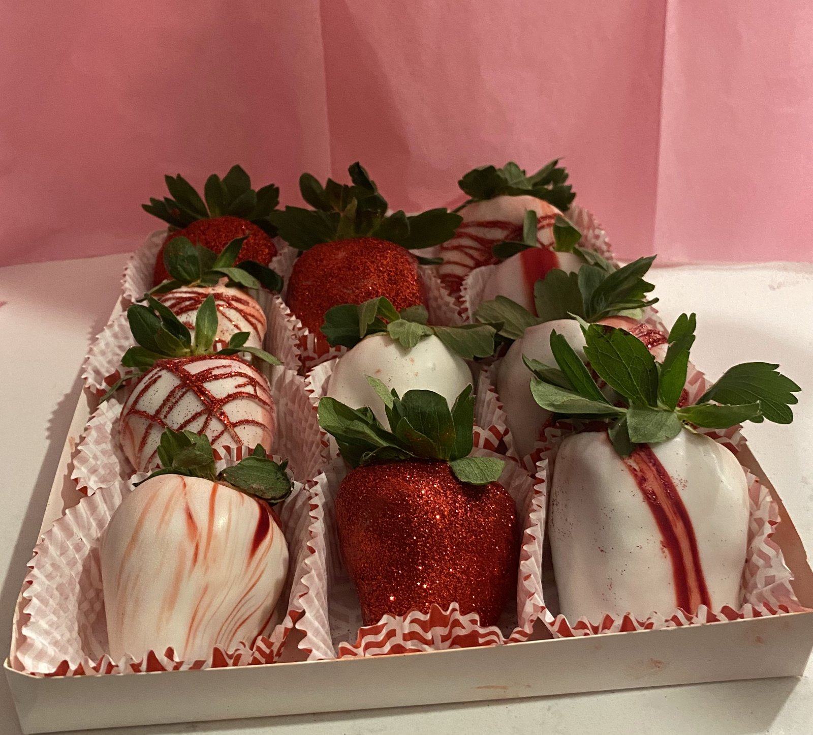 Pink box of chocolate-covered strawberries in red glitter and white with red drizzle.