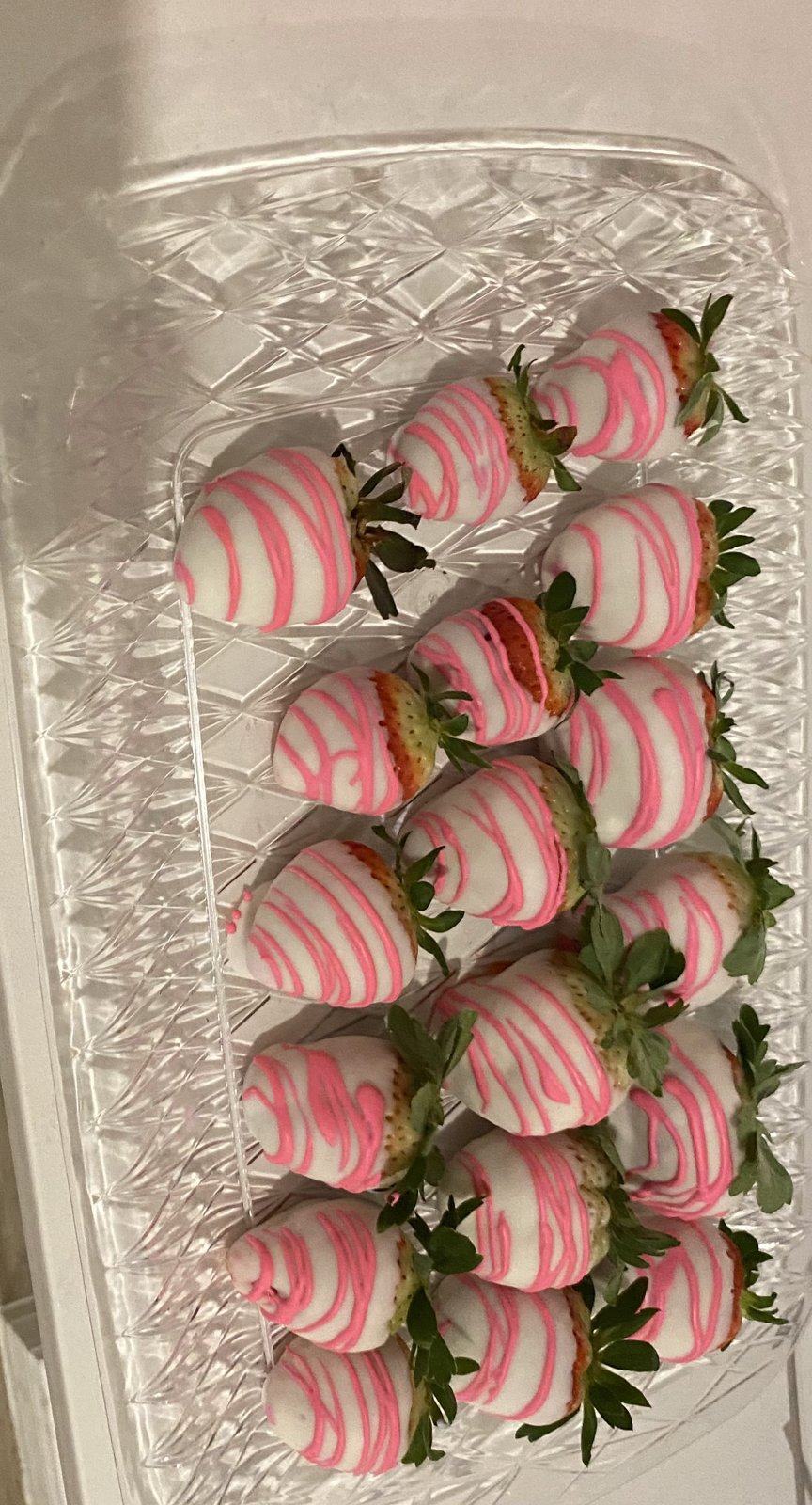 Clear container of white chocolate-covered strawberries striped in pink.