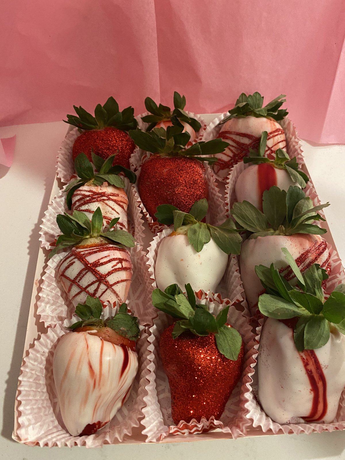 Box of red and white chocolate-covered strawberries with red and white drizzle.