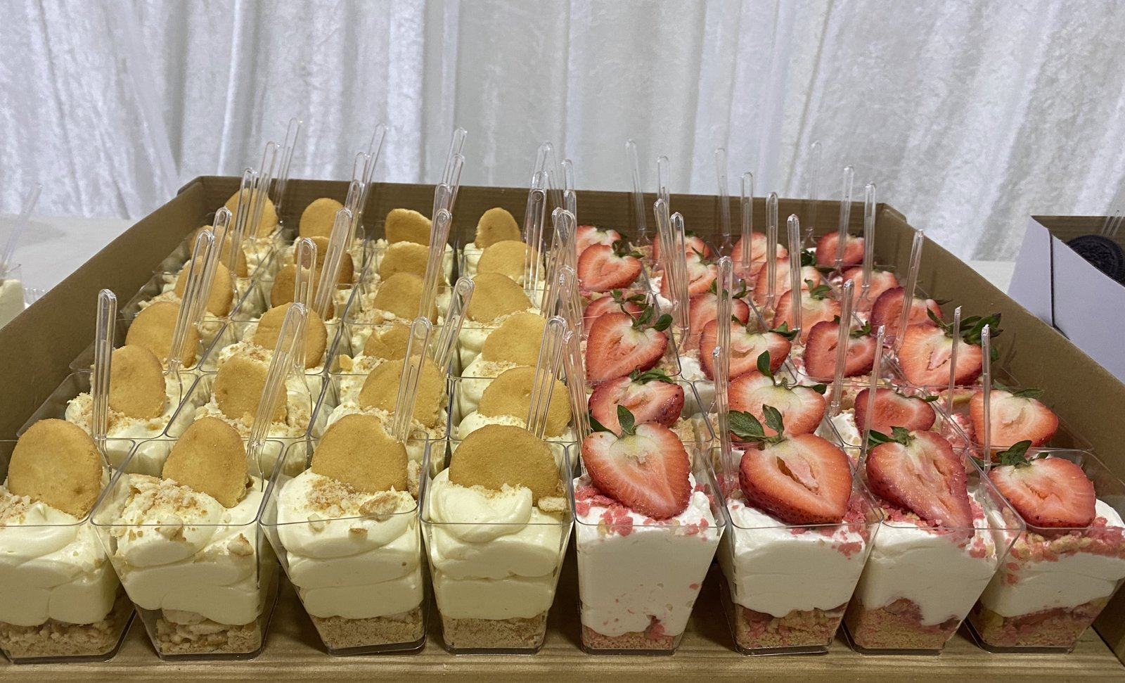 Event table lined with rows of dessert cups: cookie-topped cream, strawberry, and cookies and cream.