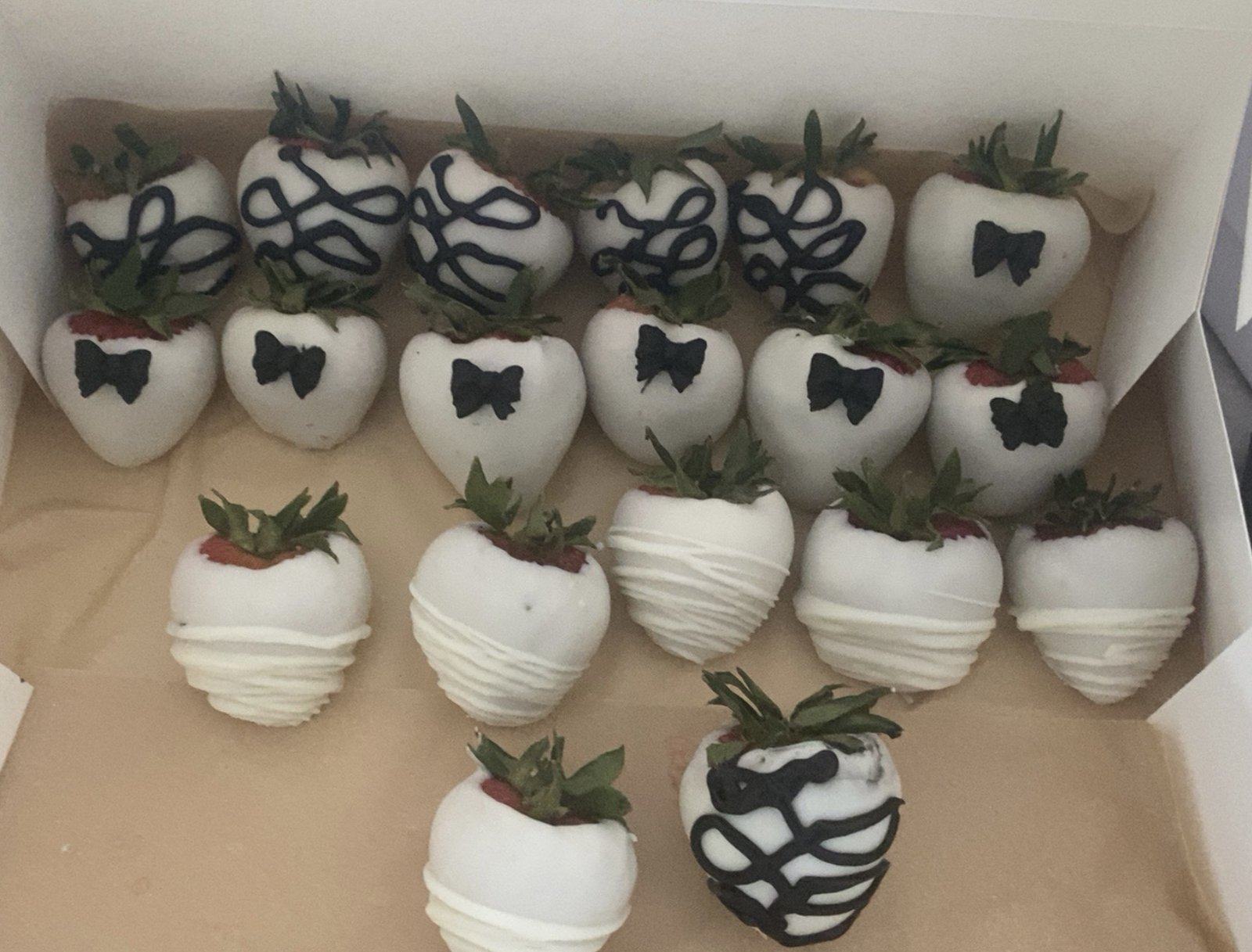 Box of white chocolate-covered strawberries with black bow ties and black and white drizzle.